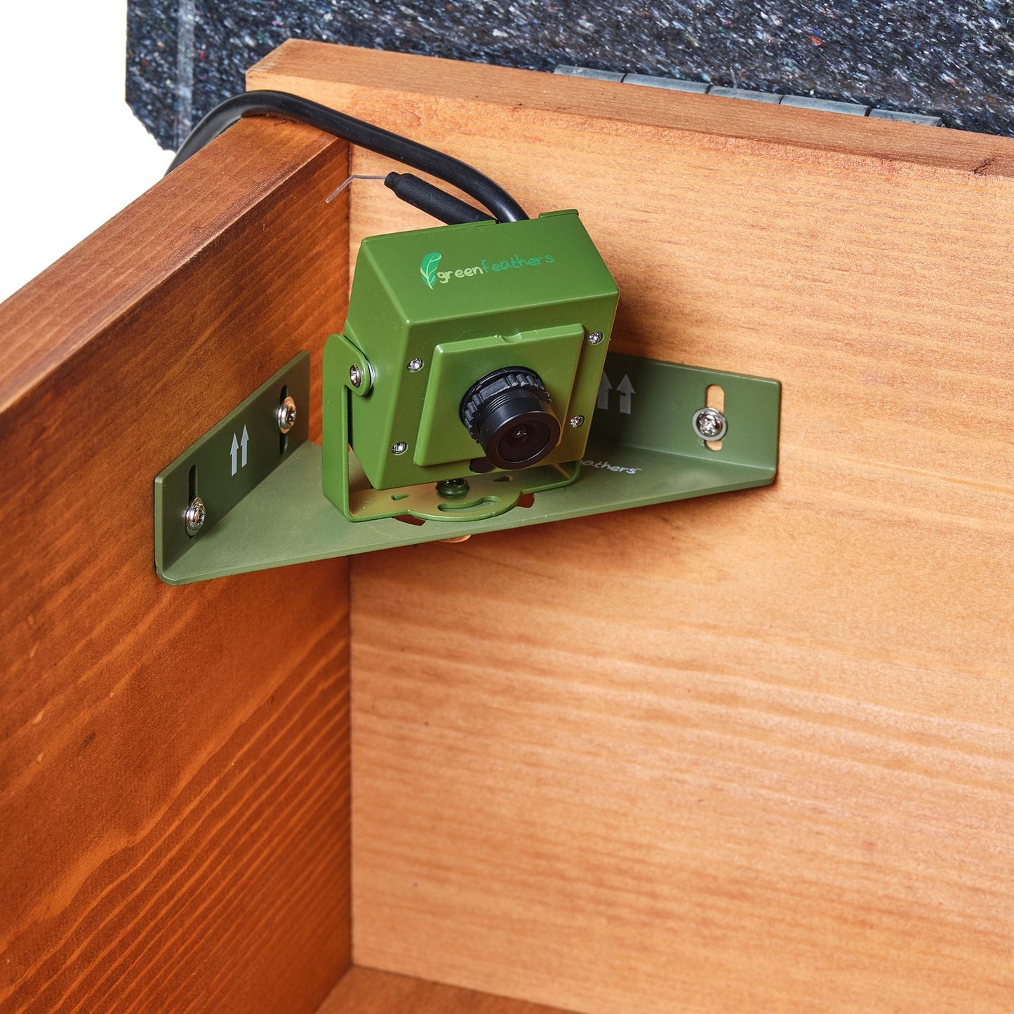 Green security camera mounted on a wooden surface with a visible brand logo.