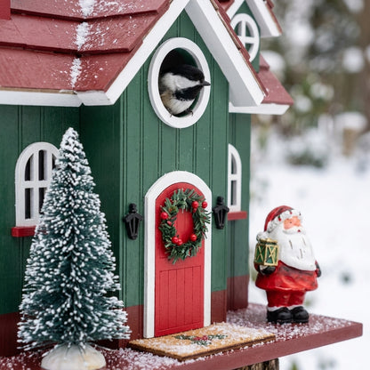Close-up of Santa figurine, frosted Christmas tree, wreath door, and Black-Capped Chickadee at the entrance hole