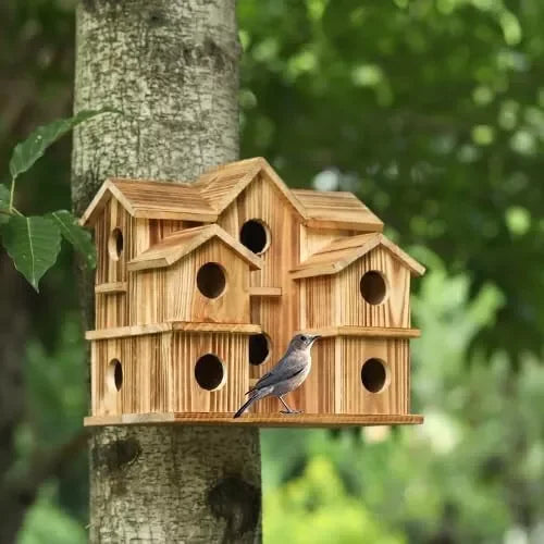 Large wooden birdhouse for outside mounted on a tree trunk with a small bird at one of the entrance holes